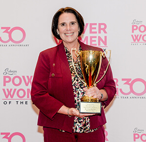 A woman in a red suit proudly holds a trophy showcasing her achievement and confidence