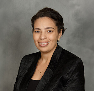 A professional woman dressed in a black blazer and black shirt, showcasing a sleek and sophisticated appearance