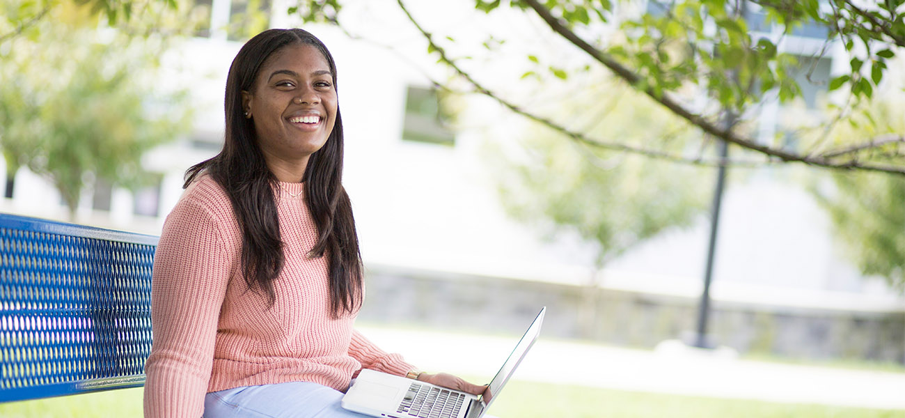 Female studnet working on a laptop outside