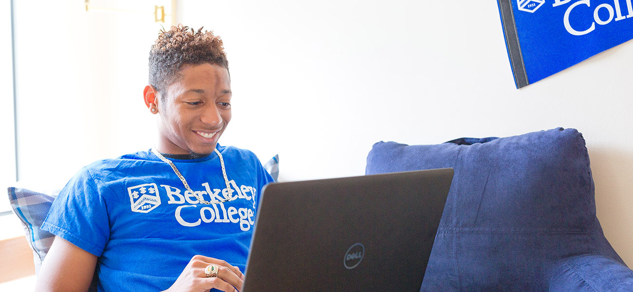 Male student working on a laptop in dorm room