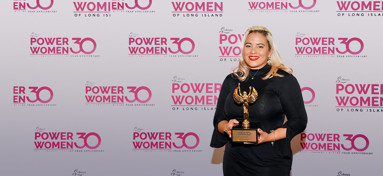 A woman proudly holds an award, celebrating her recognition as a powerful figure among women in her field