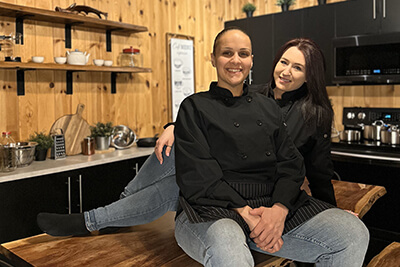 Two women engaged in conversation while seated at a wooden table in a cozy kitchen setting