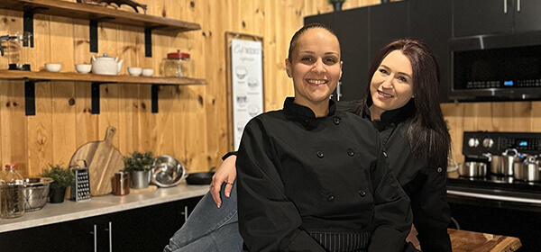 Two women engaged in conversation while seated at a wooden table in a cozy kitchen setting