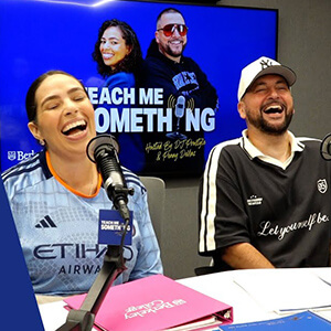 Two people are laughing in a podcast studio, wearing casual sports jerseys. The mood is joyful and lively.