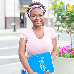 Tianna Eason smiling and holding Berkeley College notebook