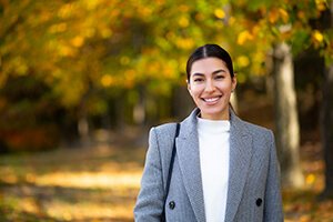 A woman in a suit and tie standing in a colorful autumn park