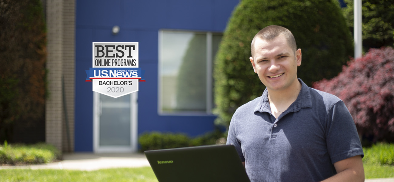 Male student working on a laptop outside