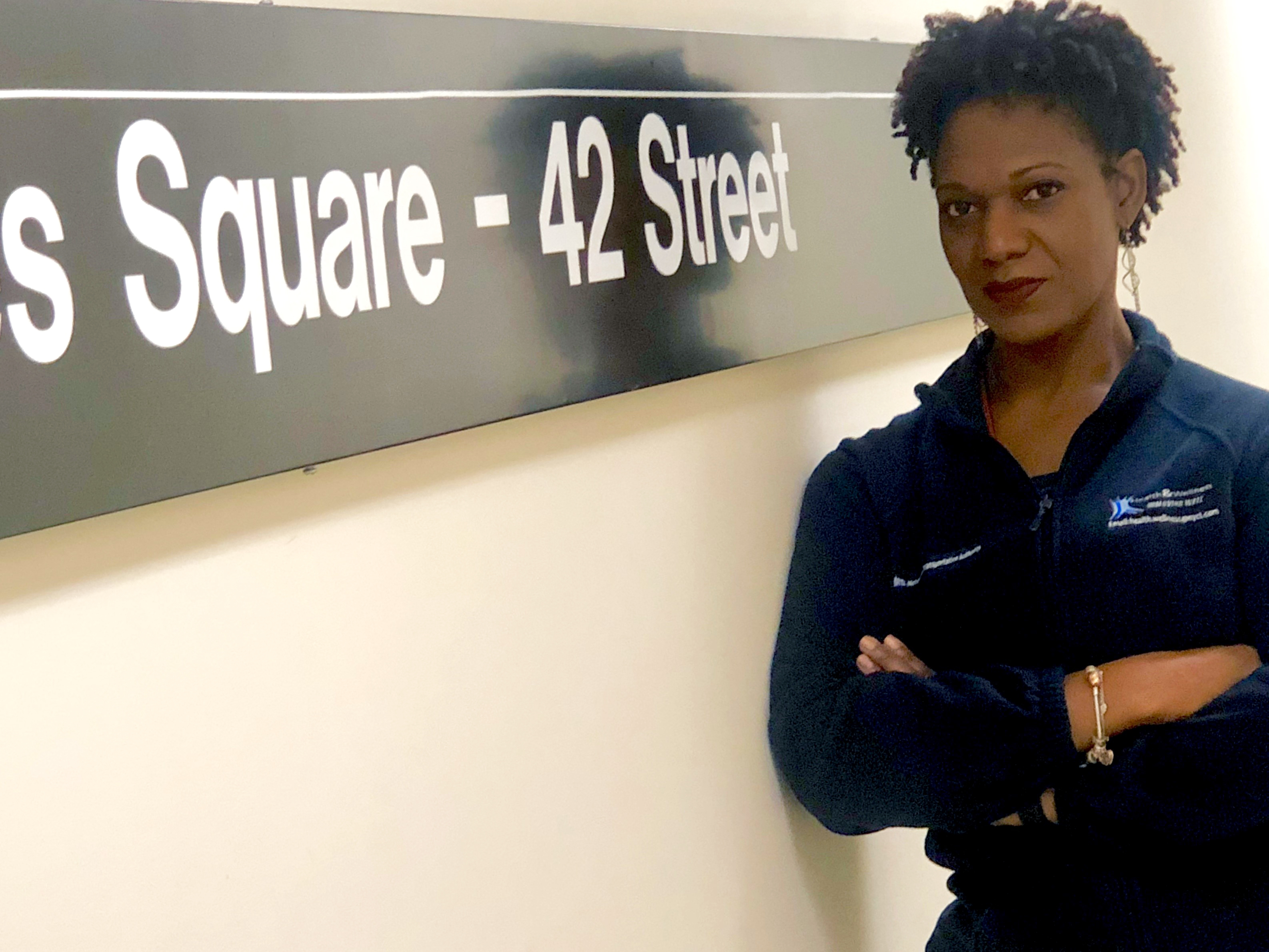 Michelle Dunn-Dawes stands by a New York City Transit sign