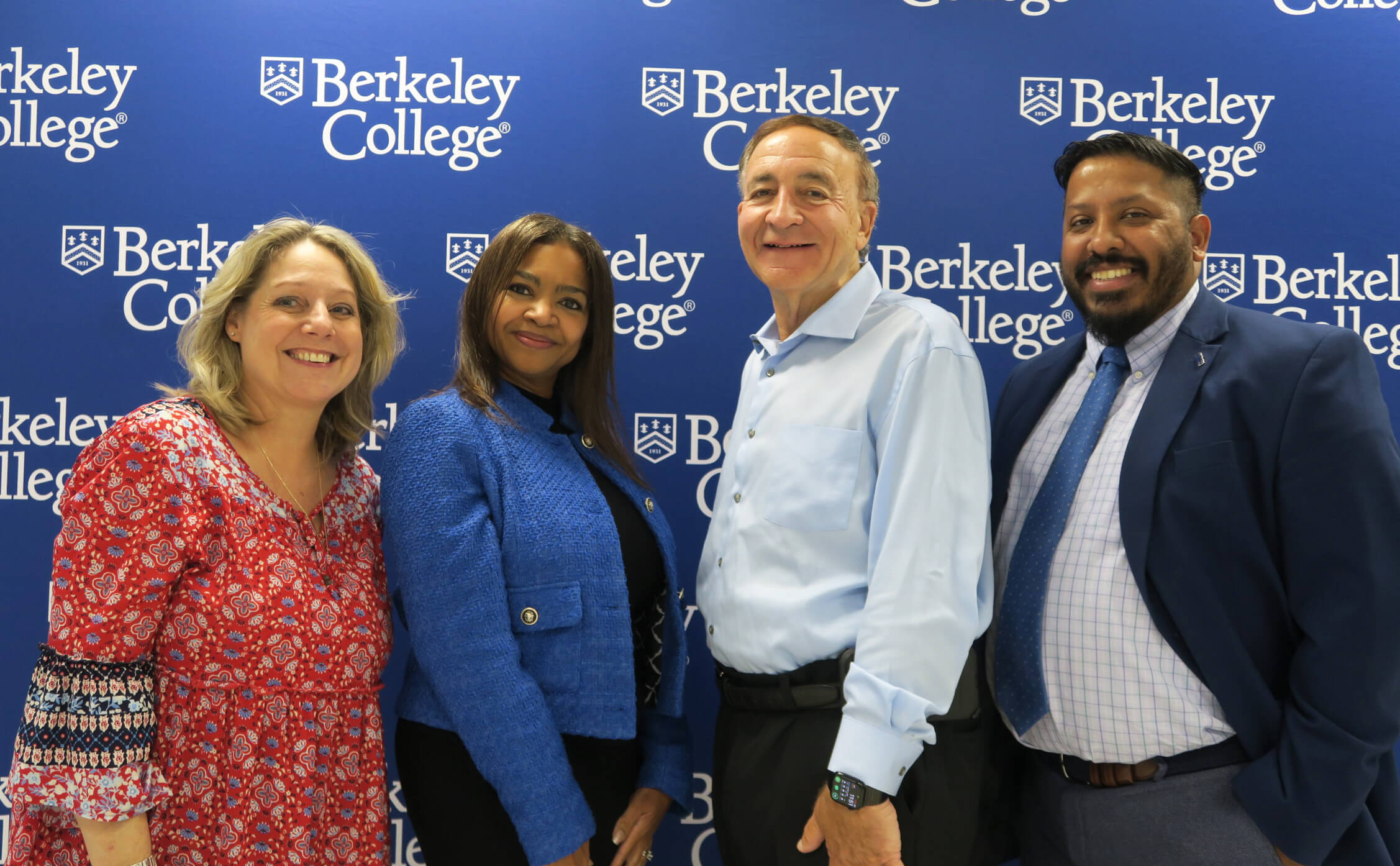 Four people standing in front of a blue Berkeley College backdrop, dressed in business and casual attire.
