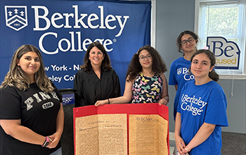 Students stand with the Provost and a trifold poster board of the US Constitution.