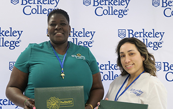Two women stand next two each smiling and holding DAISY Awards.