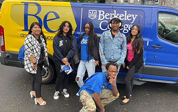 Students stand in front of a Berkeley College van and smile for a photo