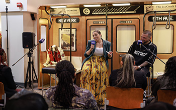 A man and a woman sit on stools in front of a fashion display