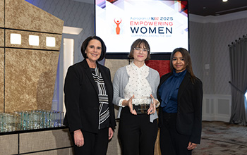 Three women stand on a stage smiling