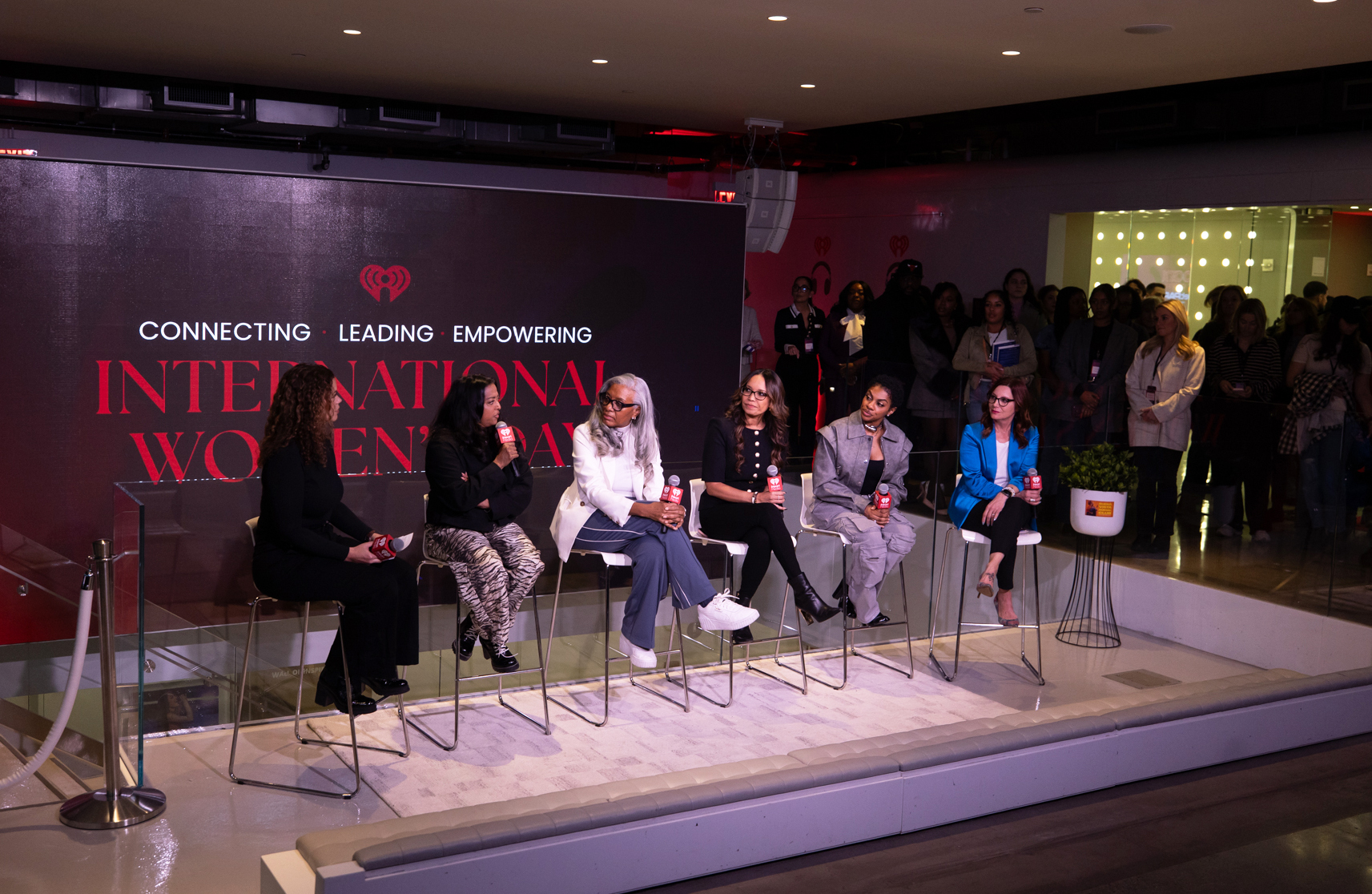 A group of women sit in chairs on a stage