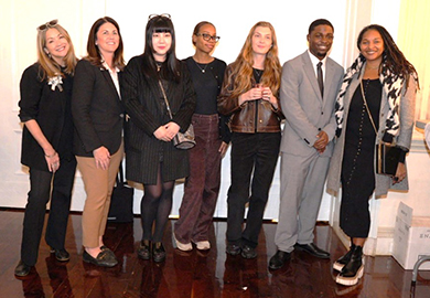 a group of men and women stand and smile