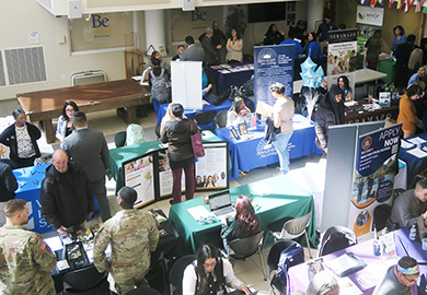 People walk around tables with signage at career fair