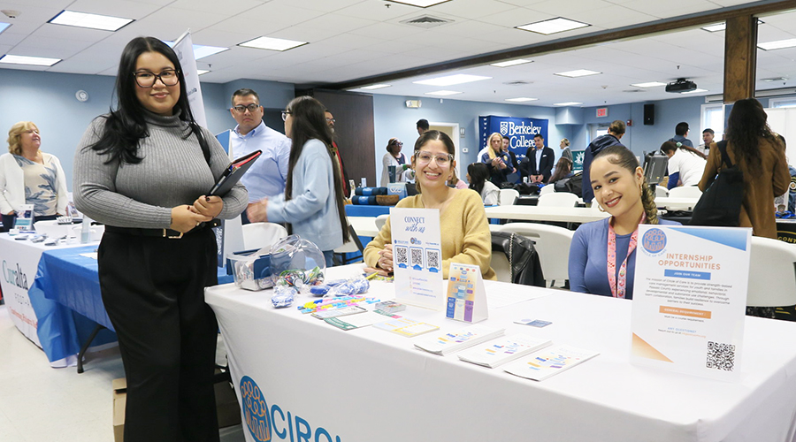 People staff information tables at a community college career and internship fair, with brochures and a “Circle of Care” display.