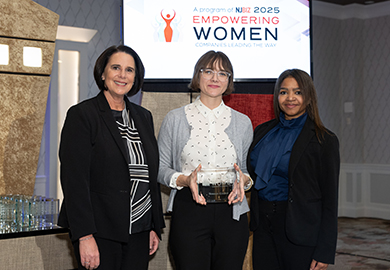 three women stand in front of a screen with an award