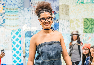a woman in a denim dress walks in a fashion show