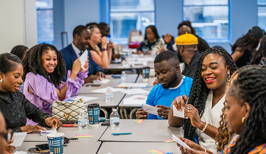 men and women sit at desks talking
