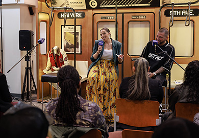 a man and a woman sit on a stage with microphones