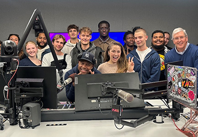 a group of students stand around a desk with radio equipment