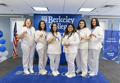 a group of students in white scrubs stand on a stage