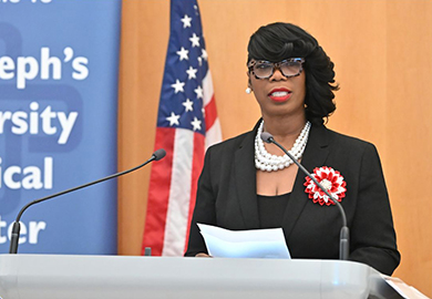 a woman in black and red speaks at a podium