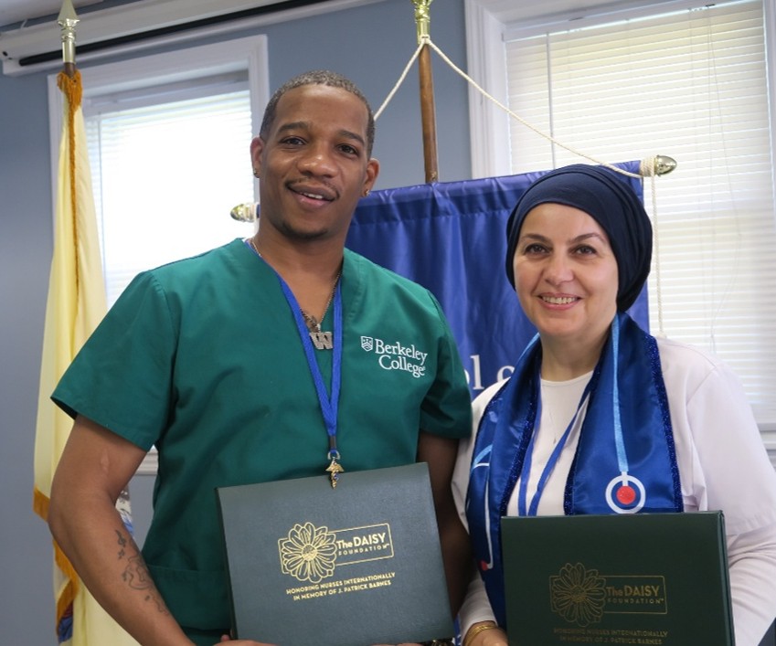 A diverse man and woman stand next to each other holding DAISY Awards.