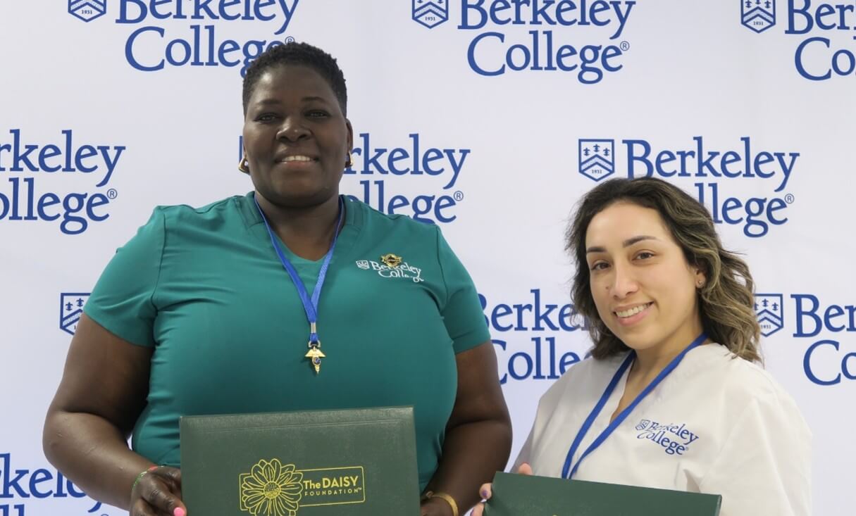 Two women stand next two each other smiling and holding DAISY Awards.