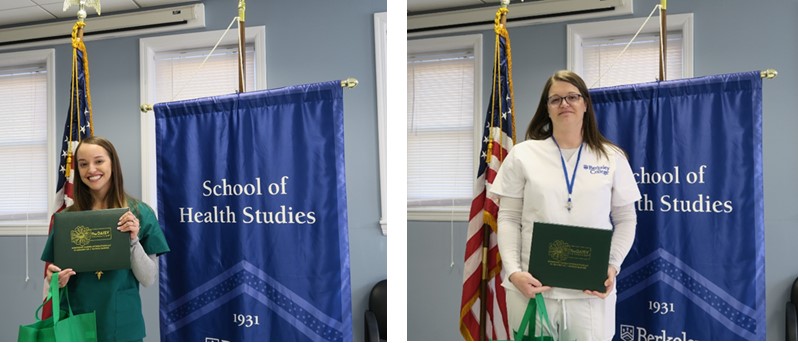 Two women stand in front of flags holding awards