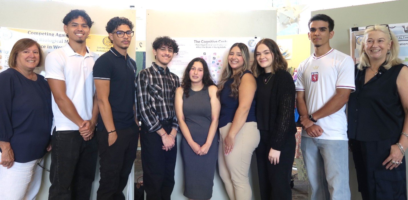 A diverse group of faculty and students stand in a line and smile for the camera.