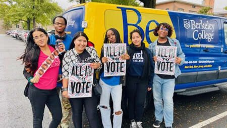 Several people gather in front of a van, each holding signs that express their thoughts and opinions