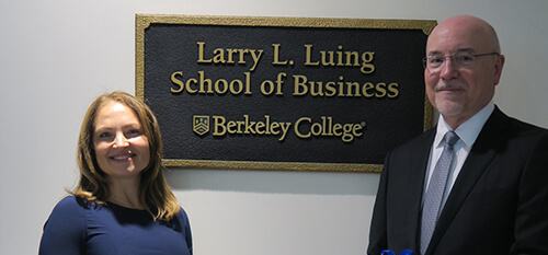 two individuals posing in front of a sign reading Larry L Luing School of Business