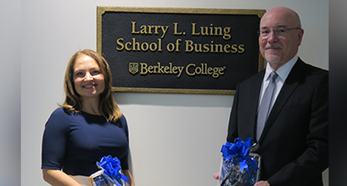 two individuals posing in front of a sign reading Larry L Luing School of Business